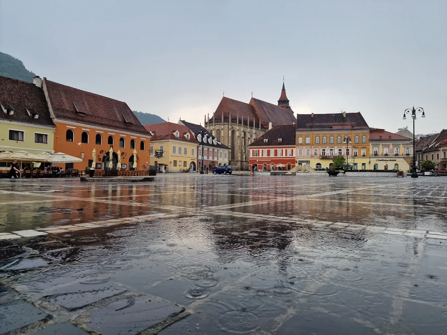 Brașov Council Square after rain, the Black Church behind the coloured merchant houses