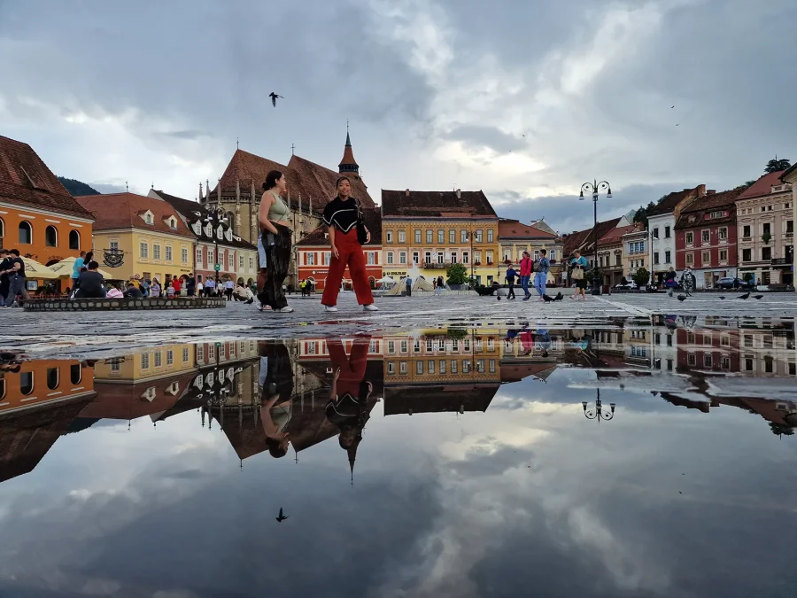 Brașov Council Square mirrored in rainwater, the Black Church behind