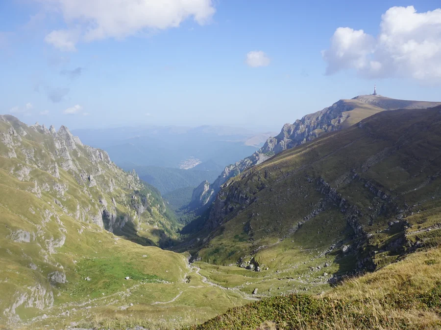 A Bucegi valley falling away below limestone ridges, the Caraiman Heroes Cross on the skyline