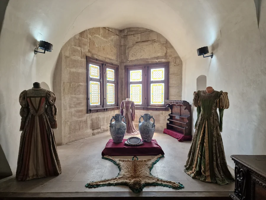 A vaulted stone room in Corvin Castle with Renaissance gowns on display