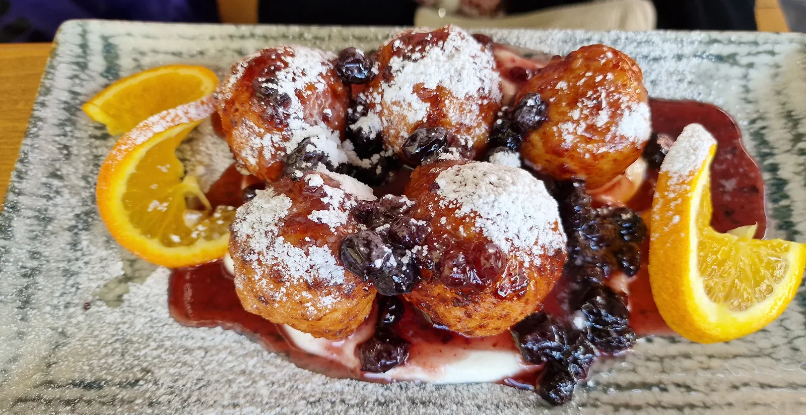 Papanași dusted with sugar, served with soured cream and berry preserve