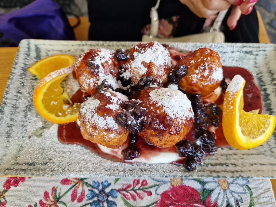 Papanași dusted with sugar, served with soured cream and berry preserve