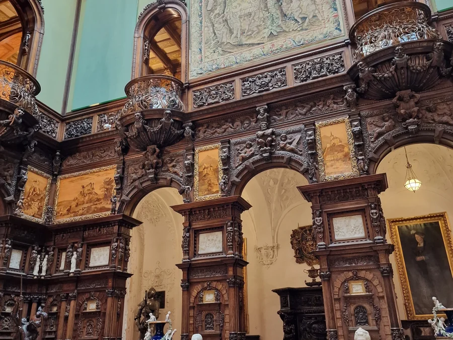 The carved walnut galleries and green walls of the Hall of Honour at Peleș Castle