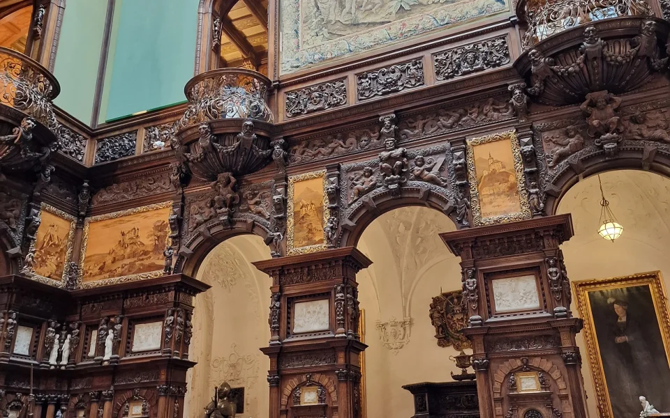 The carved walnut galleries and green walls of the Hall of Honour at Peleș Castle